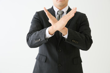 スーツを着た人が両手で×を作っている